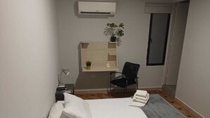 A hotel room with a bed, a desk with a chair, a small plant, and a window. - Hotel La Carpita (Medellín)