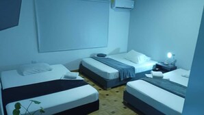 A room with two single beds, a small bedside table with a lamp, and a large window.