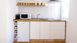 Eine kleine Küche mit Mikrowelle, Kaffeemaschine und Spüle.