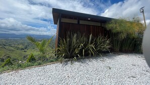 Un edificio moderno con fachada de madera y techo cubierto de césped, rodeado por un camino de grava y abundante vegetación.