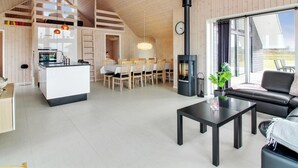 A modern interior with a kitchen, dining area, and living space, featuring wooden walls and a large window.