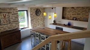 Une cuisine moderne avec un îlot central en bois, des chaises blanches et des luminaires suspendus.