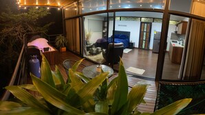 A modern, curved-roofed interior with a glass wall offering a view of a bedroom and kitchen.