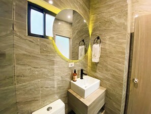 A modern bathroom with a white sink, black faucet, and a mirror with a circular frame. - Hotel Maidy Luxury (Medellín)