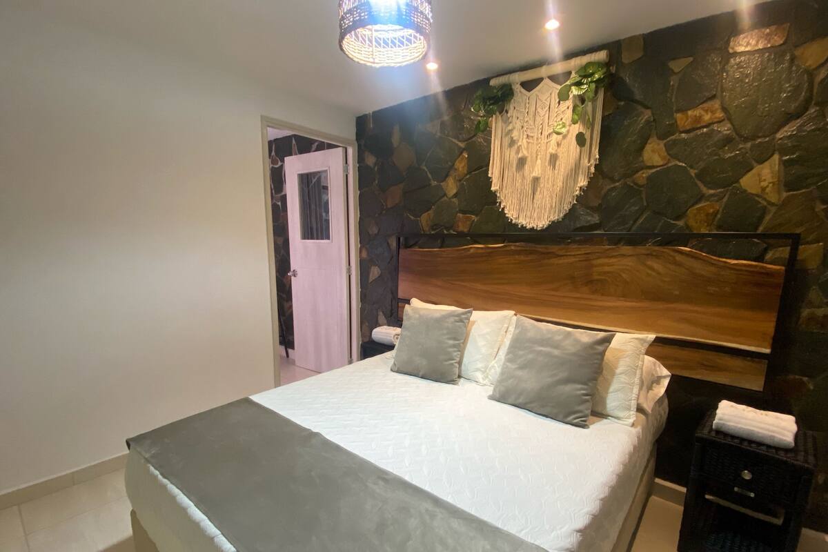 Une chambre à coucher avec un lit, une table de chevet, un mur en pierre et une porte.