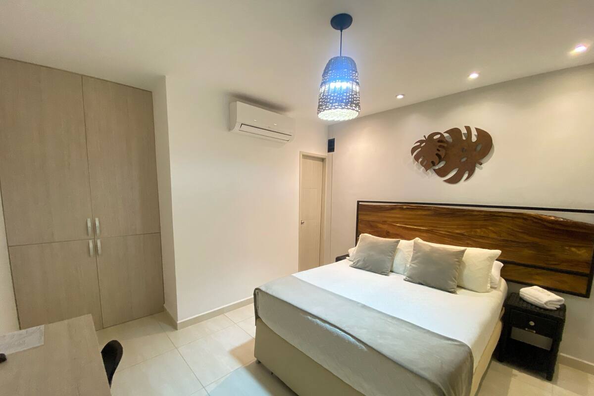 Une chambre à coucher moderne avec un grand lit, une tête de lit en bois, une table de chevet, un bureau et une armoire.