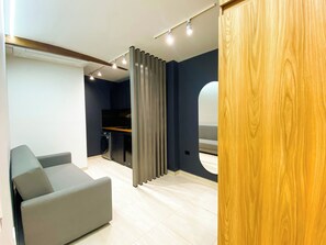 A modern room with a grey sofa, a washing machine, and a wooden panel. - Hotel Maidy Luxury (Medellín)