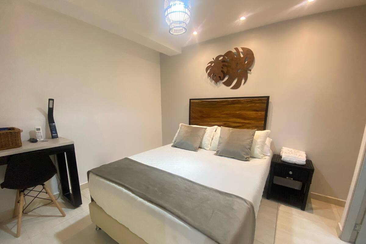 Une chambre à coucher comprenant un lit, des tables de chevet, un bureau et un élément décoratif fixé au mur.