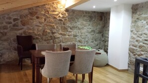 Un comedor con pared de piedra, mesa de madera y sillas grises.