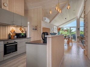 Une cuisine moderne avec un lambris en bois, un îlot central et des luminaires suspendus.