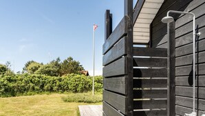 A wooden deck with a metal railing, a flagpole, and a clear sky.