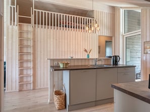 Une cuisine moderne dotée d’un îlot central, d’une banquette intégrée et d’un luminaire suspendu.