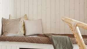 A cozy room with a wooden slat wall, a patterned sofa, and a wooden chair.