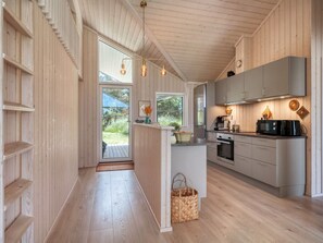 Une cuisine moderne avec des meubles en bois, un four encastré et un grand îlot central doté d’un évier.