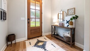 A hallway with a wooden door, a console table with decorative items, and a patterned rug. - "THE ODIN" off the OZ TRAIL (Bella Vista)