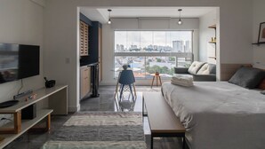 Et moderne hotelværelse med en stor seng, et fjernsyn, et skrivebord og udsigt over bybilledet gennem vinduet.