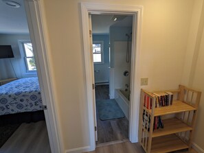A bedroom with a bed, a wooden bookshelf, and a bathroom with a shower. - Lakefront retreat w/ deck, dock, sandy beach, 4 watercraft, <6 mins to 2 beaches (Orleans)