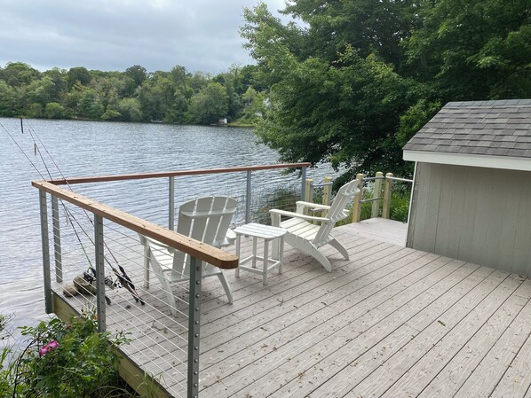 A wooden deck with a railing, two Adirondack chairs, and a small shed. - Lakefront retreat w/ deck, dock, sandy beach, 4 watercraft, <6 mins to 2 beaches (Orleans)