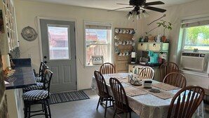 A dining area with a table set for six, surrounded by wooden chairs. A ceiling fan is above, and there are windows with blinds. - Great get away to a country home with large yard and outdoor sitting area.  (Rose Bud)