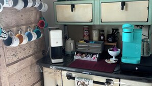 A kitchenette with a coffee maker, a coffee grinder, and a teal water bottle. - Great get away to a country home with large yard and outdoor sitting area.  (Rose Bud)