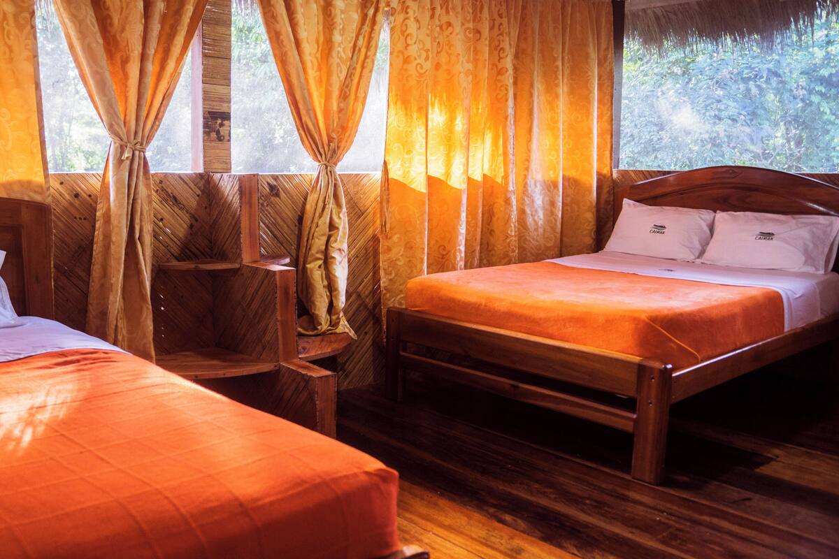A room with two wooden beds, a wooden chair, and a window with curtains.