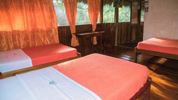 A room with two beds, a wooden desk, and a window with curtains. - Caiman Lodge (Palma Roja)
