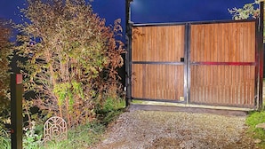 Une entrée fermée par un portail, avec un chemin de gravier menant à une clôture en bois.