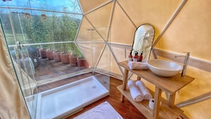 Une salle de bain moderne avec une douche en verre, un meuble-lavabo en bois et une vue sur la verdure.