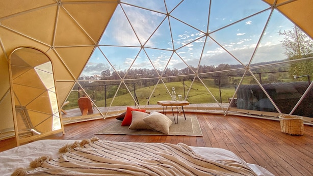 Une pièce chaleureuse avec une grande fenêtre, un plancher en bois et un lit recouvert d’une couverture à rayures.