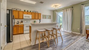 Una cucina con mobili in legno, un frigorifero bianco, un forno a microonde e un bancone con sgabelli.