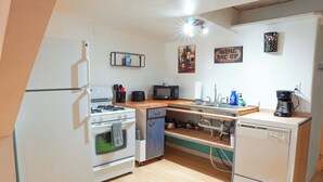 Une cuisine compacte équipée d’un réfrigérateur, d’une cuisinière, d’un four à micro-ondes et d’un lave-vaisselle. On y trouve également des placards, un plan de travail et un évier.