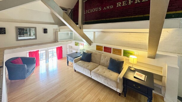 Un salon spacieux avec un plafond haut, un canapé, un fauteuil et une petite table.