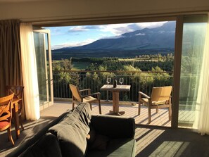 Ein Balkon mit einer Couch, Stühlen und einem Tisch mit Weingläsern und einer Weinflasche.