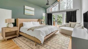 Une chambre à coucher moderne, avec un lit, des tables de chevet, un canapé et de grandes fenêtres.