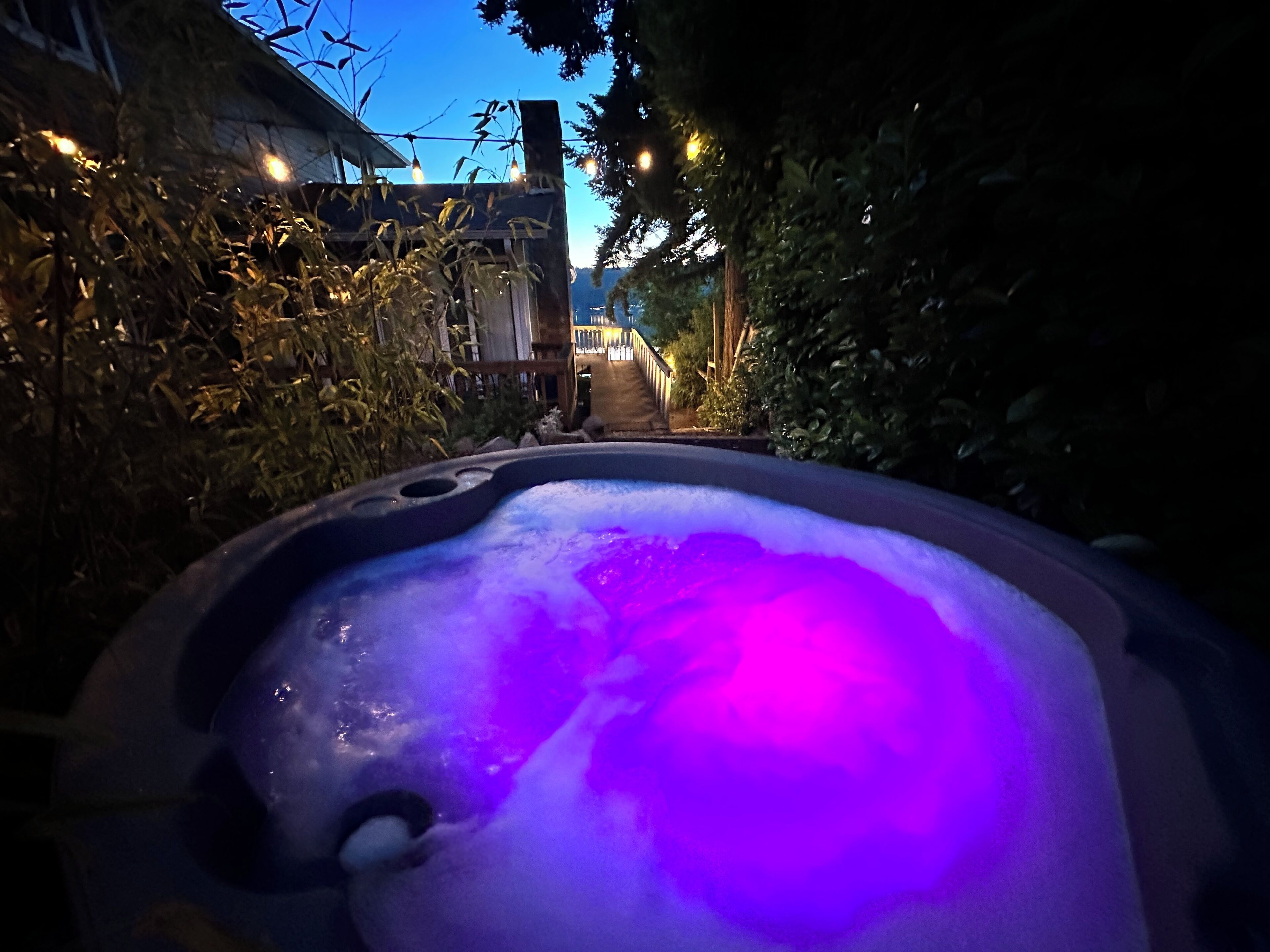 A hot tub with a view of a building and trees in the background.