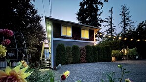 A modern house with a gravel driveway, surrounded by well-maintained hedges and flowering plants.