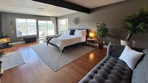 A spacious bedroom with a large bed, a sofa, a fireplace, and a view of a lake.