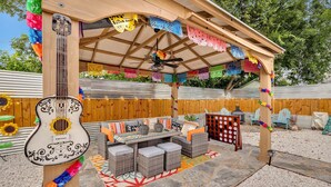 An outdoor patio with a covered seating area, a guitar, and colorful decorations. - Coco House rental home sleeps 6, ample outdoor seating, jacuzzi and a golf cart! (San Antonio)