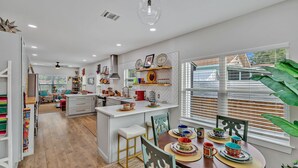 A modern kitchen with a central island, wooden flooring, and a dining area with colorful tableware. - Coco House rental home sleeps 6, ample outdoor seating, jacuzzi and a golf cart! (San Antonio)