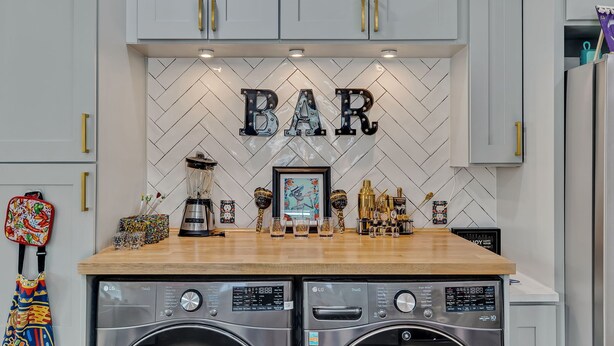 A kitchen with a herringbone tile backsplash, a 'BAR' sign, and two LG washing machines. - Coco House rental home sleeps 6, ample outdoor seating, jacuzzi and a golf cart! (San Antonio)