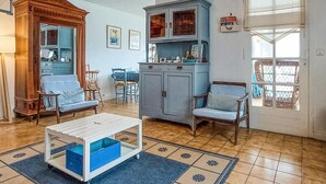 A living room with a wooden cabinet, a blue sofa, a white coffee table, and a dining area with chairs. - 2 bedroom gorgeous home in St-Georges-de-Didonn (St-Georges-de-Didonn)