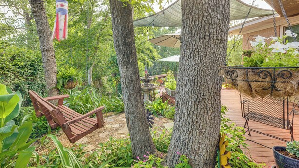 Ein Garten mit einer Holzschaukel, hängenden Dekorationen und einer Pergola.