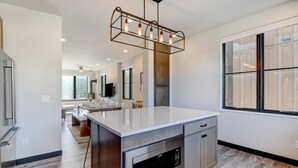 A modern kitchen with a large island, stainless steel appliances, and a pendant light fixture. - Downtown WP Loft 21 I Rooftop Hot Tub & Lounge I Great Views I Bunks I Discounted Attractions (Winter Park)