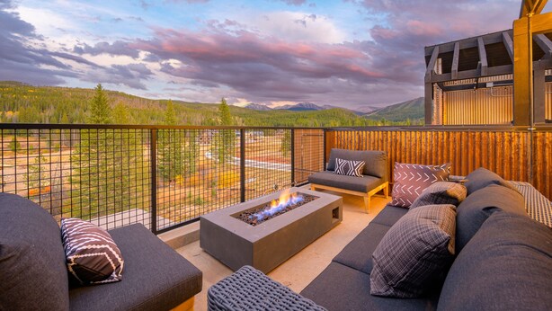 A balcony with a fire pit, outdoor seating, and a view of a forested mountain range. - Downtown WP Loft 21 I Rooftop Hot Tub & Lounge I Great Views I Bunks I Discounted Attractions (Winter Park)