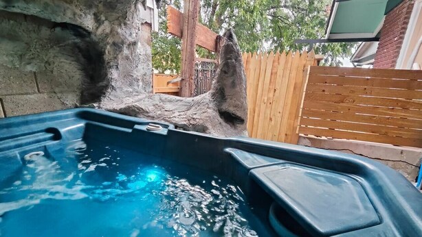 Ein Whirlpool mit einer Holzterrasse und einem Baum im Hintergrund.