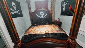 Ein Himmelbett mit einem Totenkopf- und Knochenkreuz-Kopfstück, umgeben von nautisch inspirierten Dekorationen.