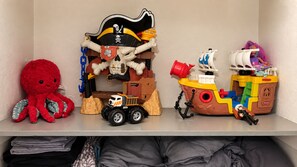 A shelf with various toys including a pirate ship, a truck, and a red octopus.