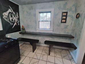 A kitchen with a black countertop, two black benches, a window, and a wall with a skull design. - Pirate Seeking crew. Downtown with hot tub! (fort smith)
