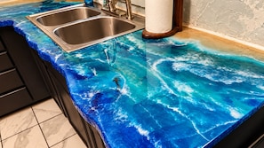 A kitchen with a blue marble countertop and stainless steel sink.
