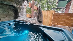 A hot tub with a wooden fence and a tree in the background.